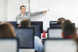 Smiling male instructor giving a lecture in computer lab.
